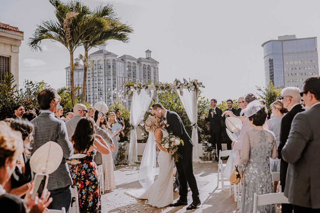 Newlyweds have their first kiss during a petal toss at their wedding.