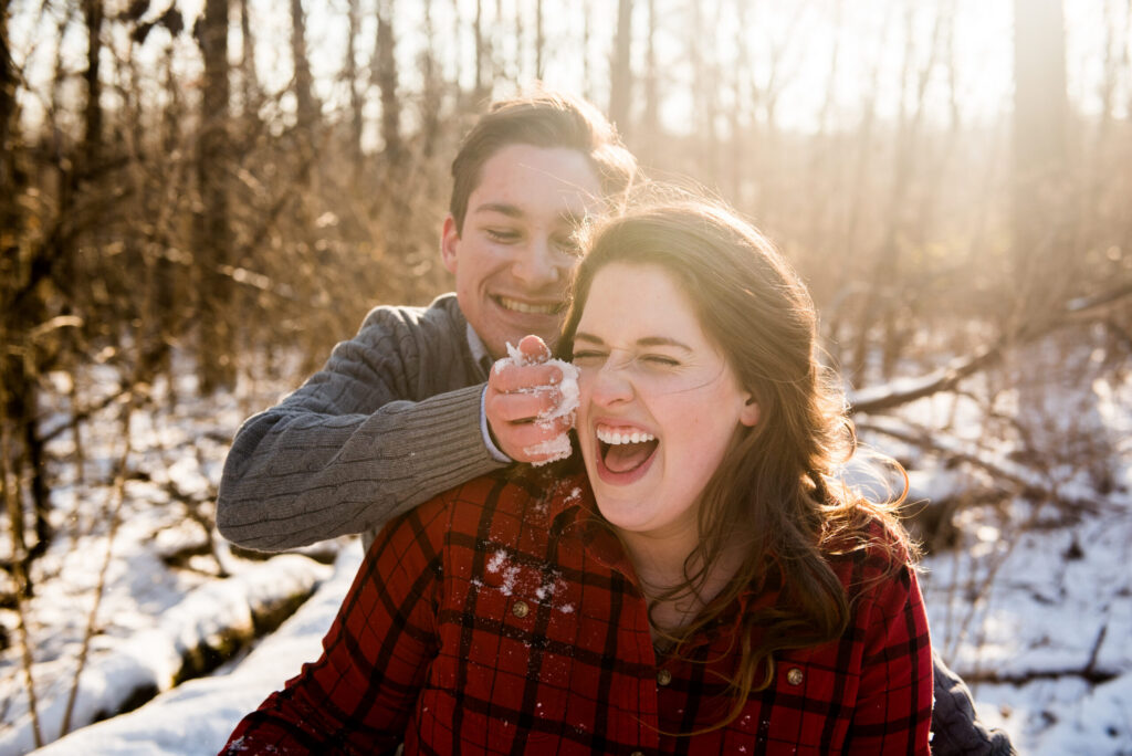 Couple laughing in snow during engagement session by Green Apple Weddings