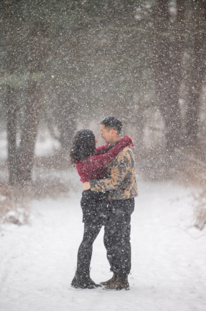 Couple in falling snow engagement portrait by Roc Focus