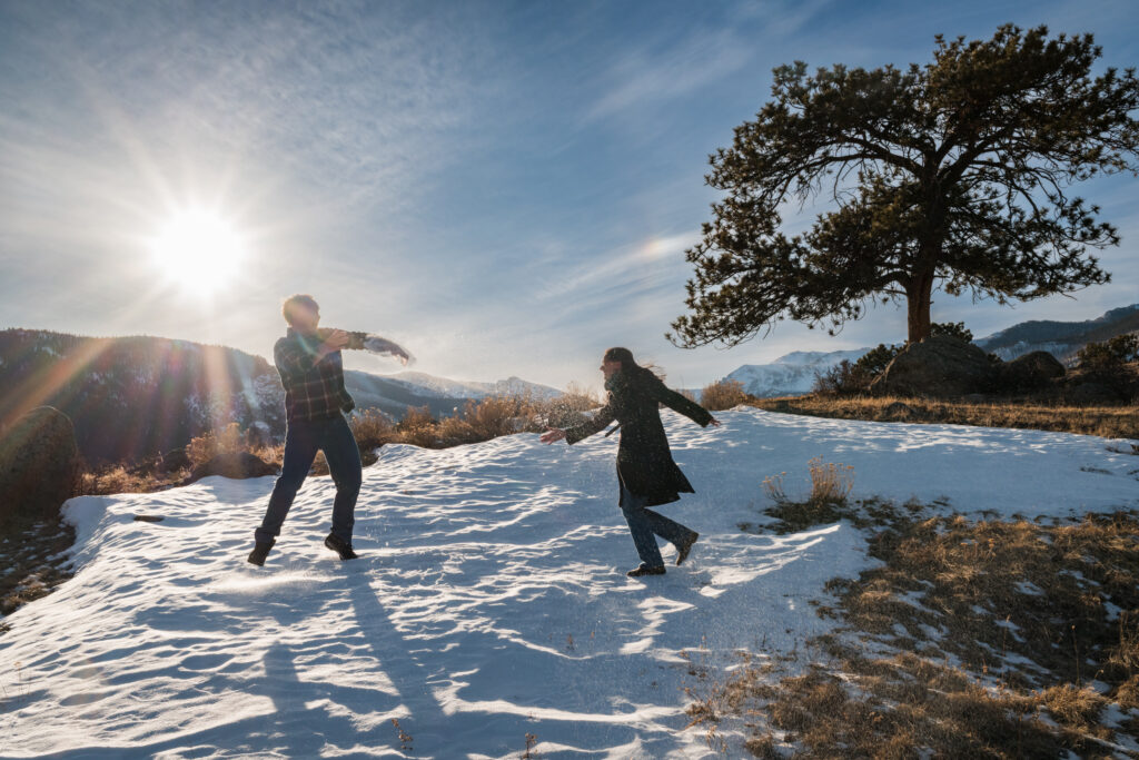 Couple playing in snow during engagement session by Gretchen Troop